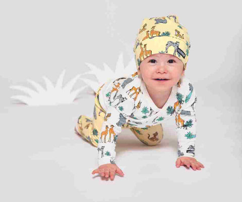 An infant crawling towards the camera wearing a safari themed outfit in neutrals - baby outfit available at Pine Centre Mall in Prince George BC
