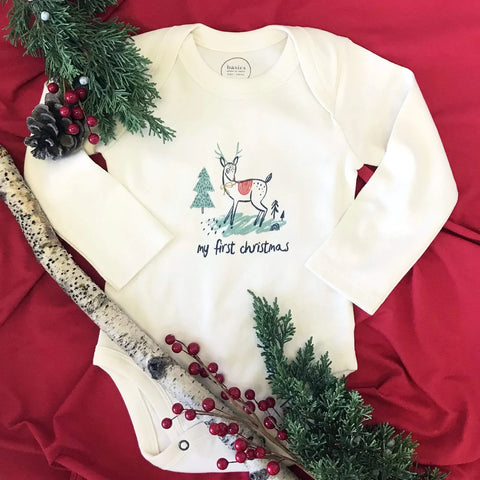 Baby's First Christmas Onesie on a red background with Christmas tree decor