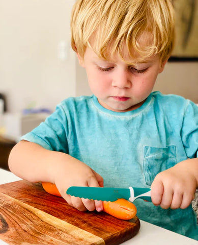 Kiddikutter knife being used by toddler to cut a carrot