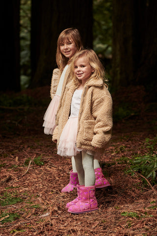 Kids in bright pink Uggs in the forest for winter boot collection