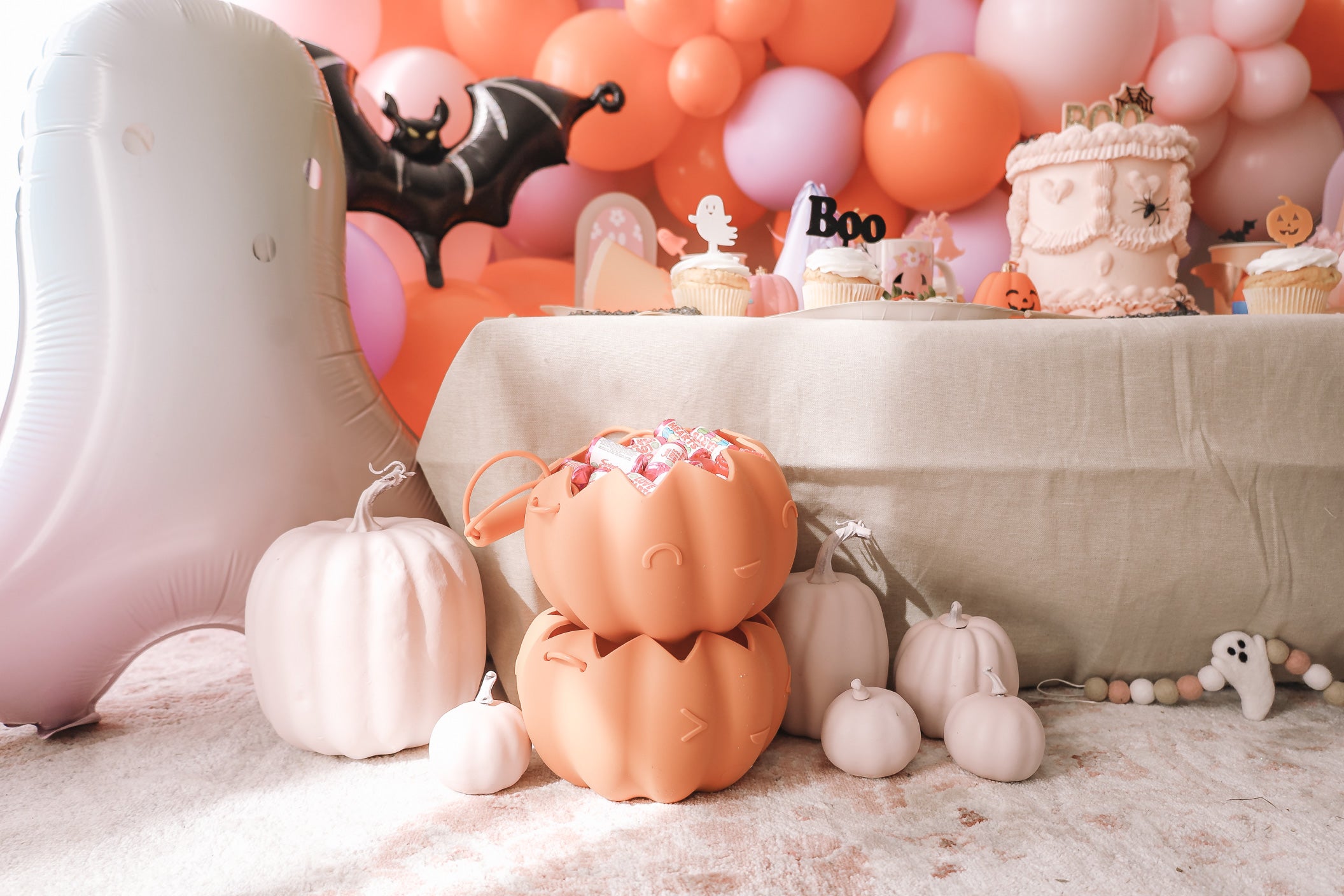 Halloween party decorations with pink pumpkins and a pastel ghost balloon