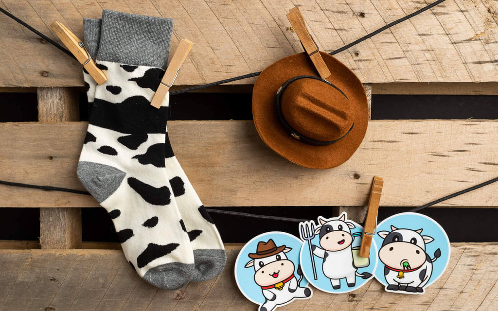 cow socks, cowboy hat, and cow stickers hanging by clothes pins