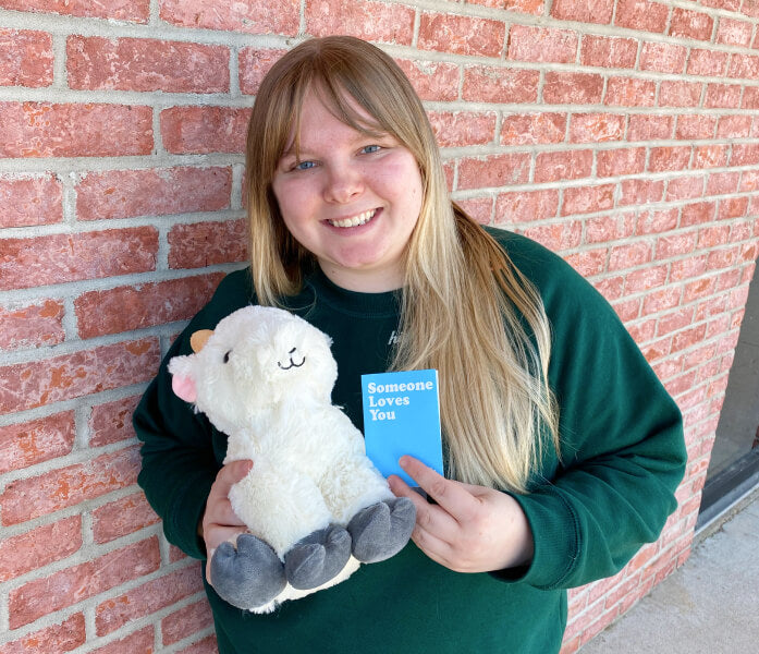 woman holding goat stuffed animal and note card