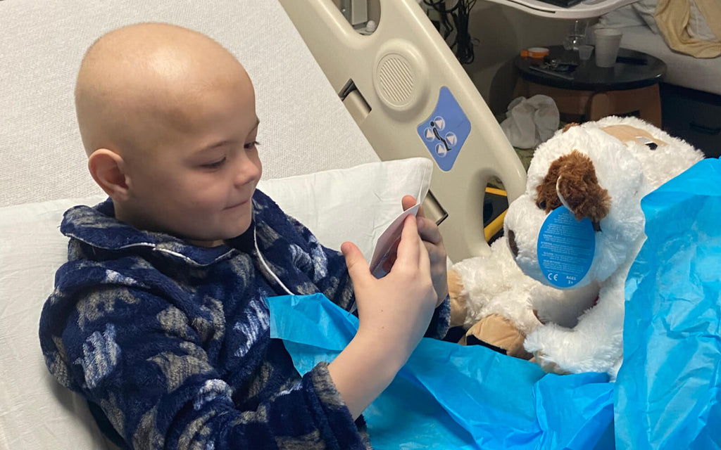 child in hospital reading notecard and receiving a donated stuffed animal