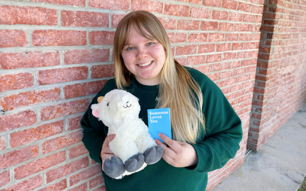 Woman holding Gus the Goat stuffed animal with notecard