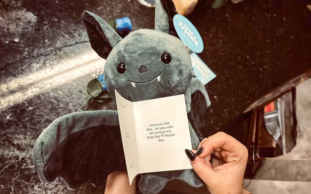 An image of hands holding Binks the Bat and a notecard