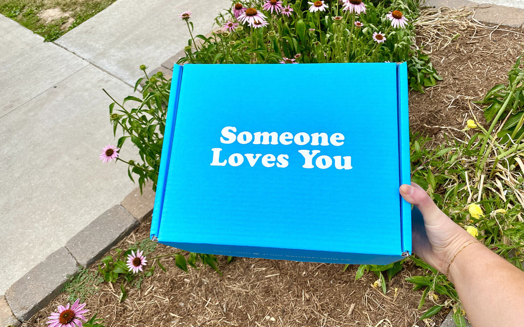 Image of a hand holding a "Someone Loves You" care package