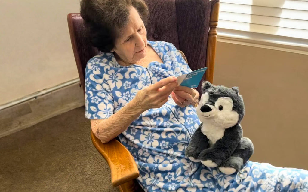 Image of an older woman reading a notecard with Winston the Wolf sitting on her lap
