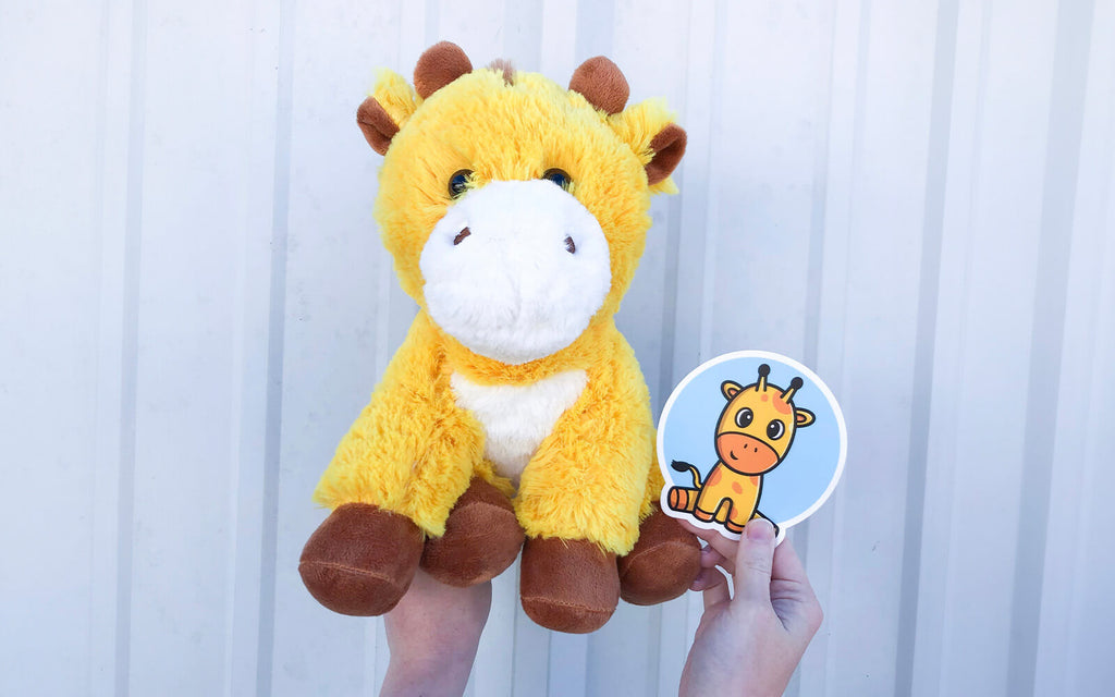 An image of hands holding George the Giraffe and matching sticker