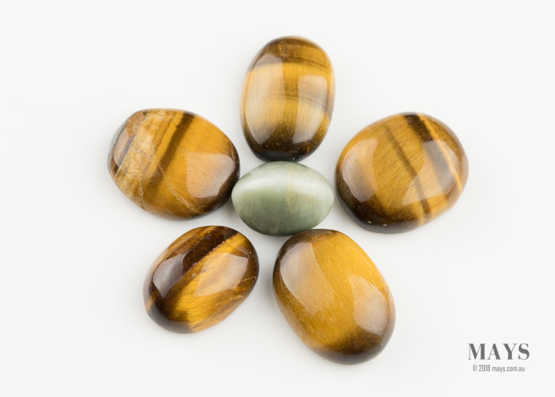 A cat eye ornamental gemstone surrounded by tiger eye gemstones.