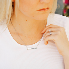 woman wearing a silver nurse bar necklace personalized with her name and medical credentials