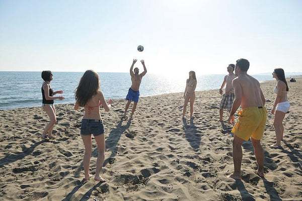 jóvenes jugando voleibol en la playa