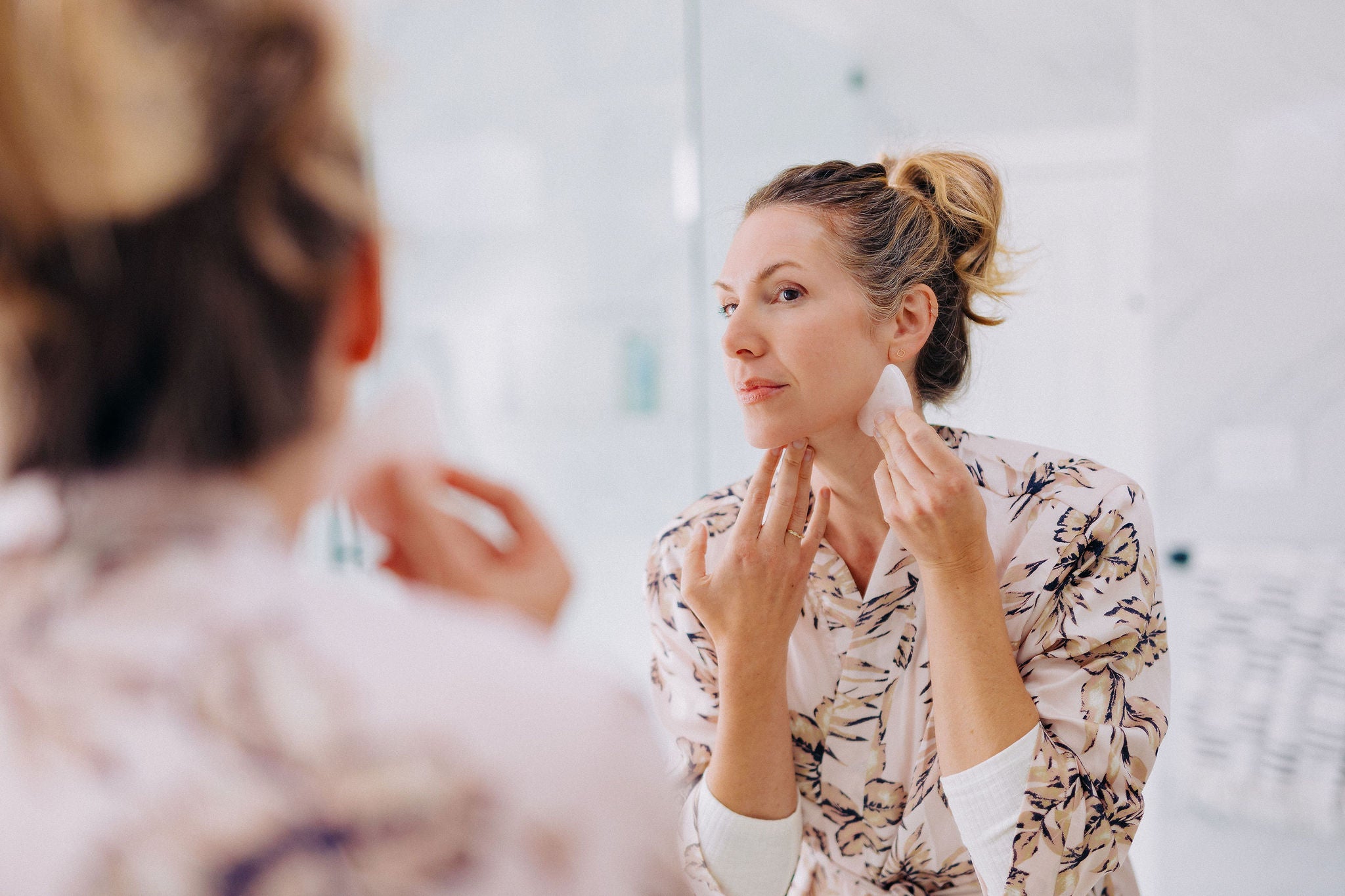 woman in the mirror using a gua sha