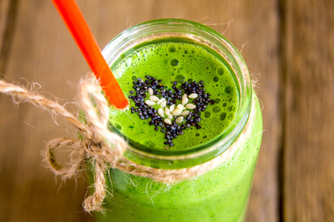 green smoothie in a mason jar topped with chia seeds in the shape of a heart