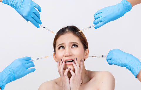 woman with fearful look and her hands by her mouth while many hand point needles at her