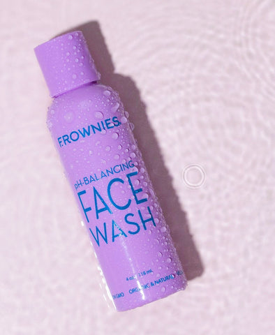 Frownies pH balancing face wash in purple bottle on pink background