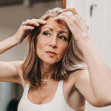 woman applying Frownies Facial Patches to forehead wrinkles