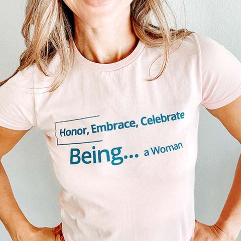 woman wearing a pink tshirt with words "honor, embrace, celebrate being ...  a woman"