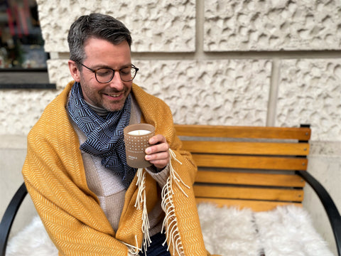 Torben macht es sich hygge in der Advents-Zeit: Mit einer Duftkerze von Skandinavisk, einer kuscheligen Decke von Klippan und einem weichen Schal von Fortschritt Berlin. 