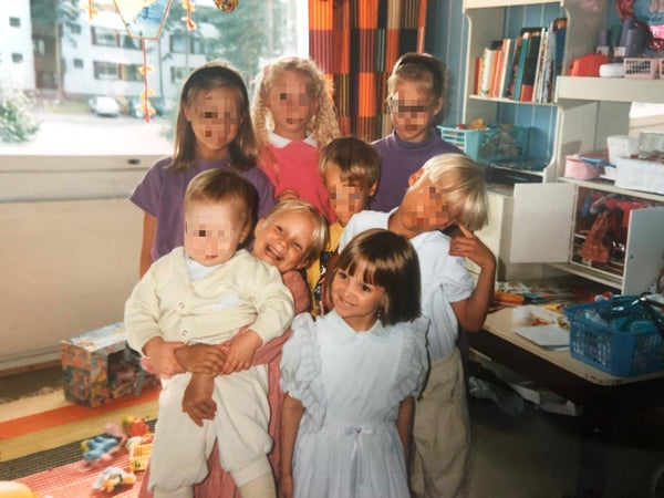 Nascha und ihre Schwester mit Freundinnen und Freunden im Kinderzimmer in Finnland vor roten Vorhängen von Marimekko. 