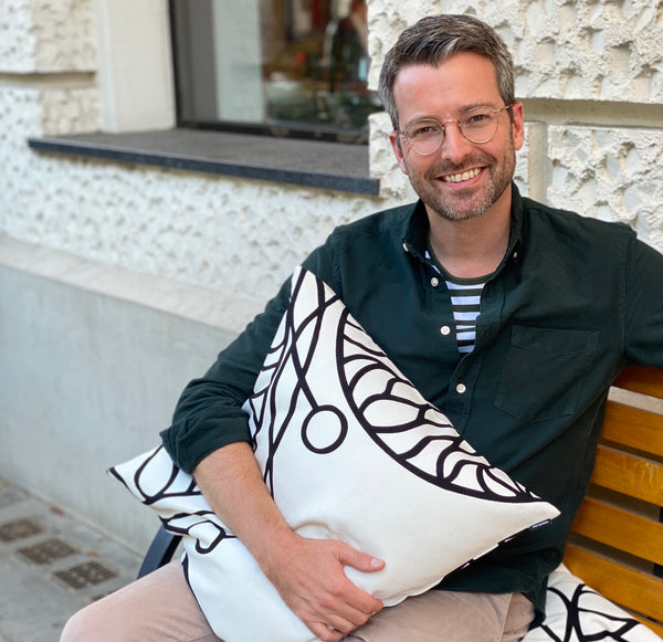 Torben Pahl, Chef vom Team HARTOG Berlin, lernte Marimekko mit dem Bottna-Muster kennen. Hier hält er ein Kissen im Arm mit Bottna. 