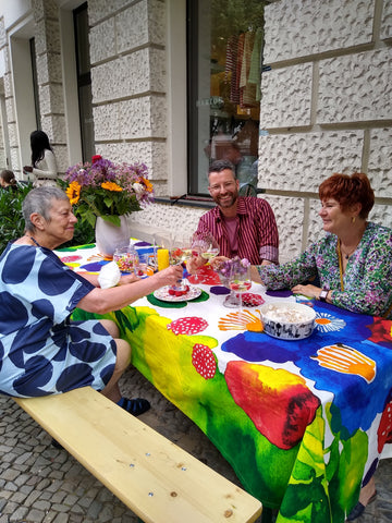Dank niedriger Inzidenzen konnten wir Mittsommer draußen feiern, Torben spricht mit Kundinnen am geschmückten Tisch. 