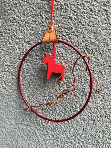 Nordische Weihnachts-Deko: Strups-Ring aus Dänemark naturnah dekoriert mit einem kleinen Ast und einem roten Dala-Pferd aus Schweden.