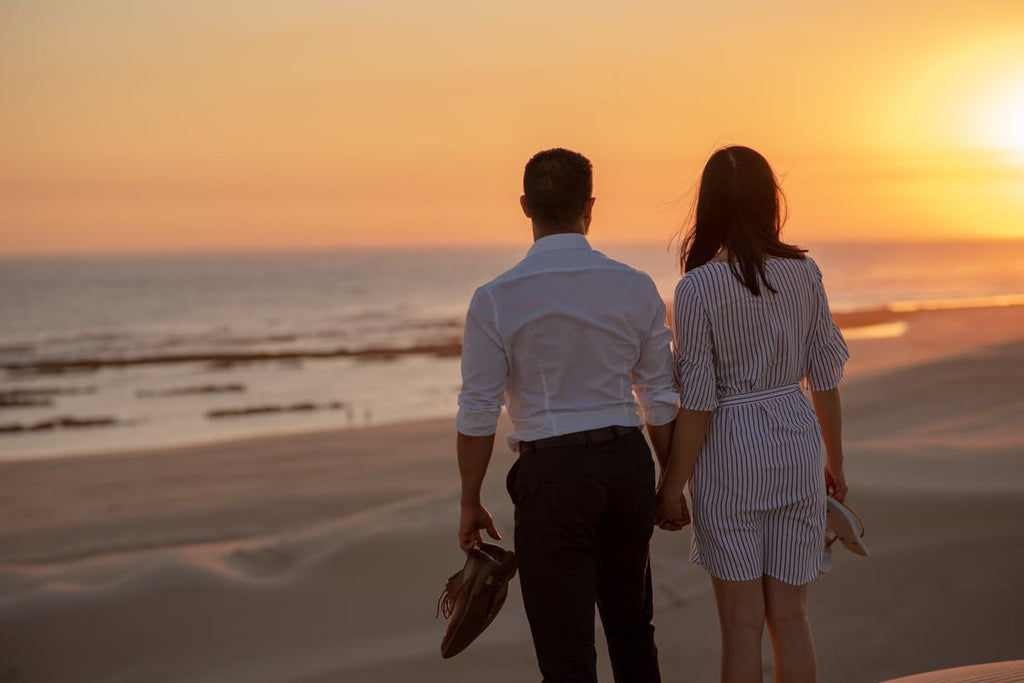 couple standing on the beach at sunset