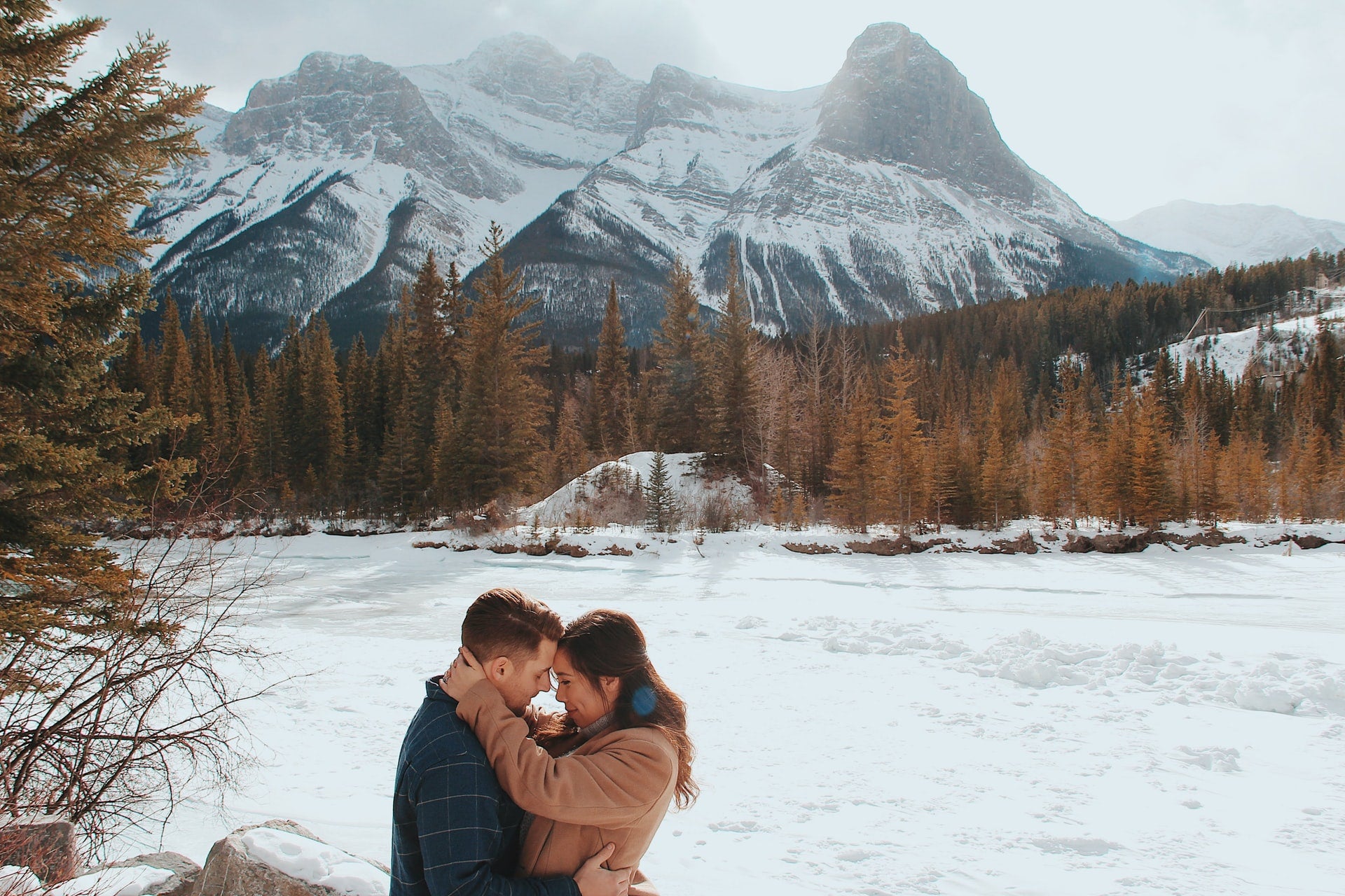 couple embracing each other with a beautiful snowy mountain in the background
