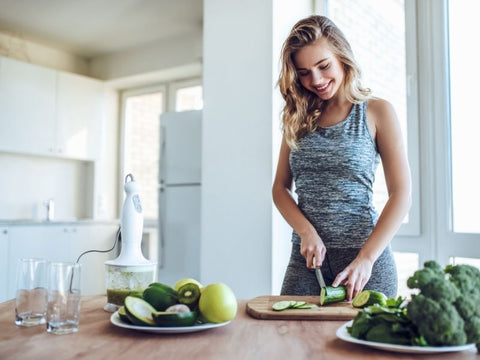 young woman making a green smoothie - importance of food quality