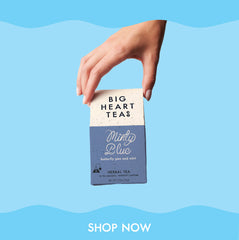 Hand holding minty blue tea on blue background. CTA shop now