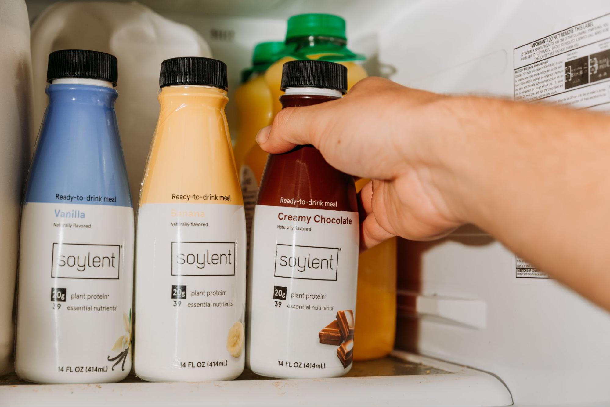 Hand taking out Soylent protein drink from fridge