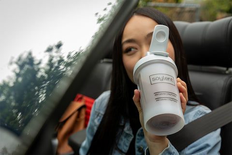Woman drinking chocolate complete meal in a Soylent blender bottle.