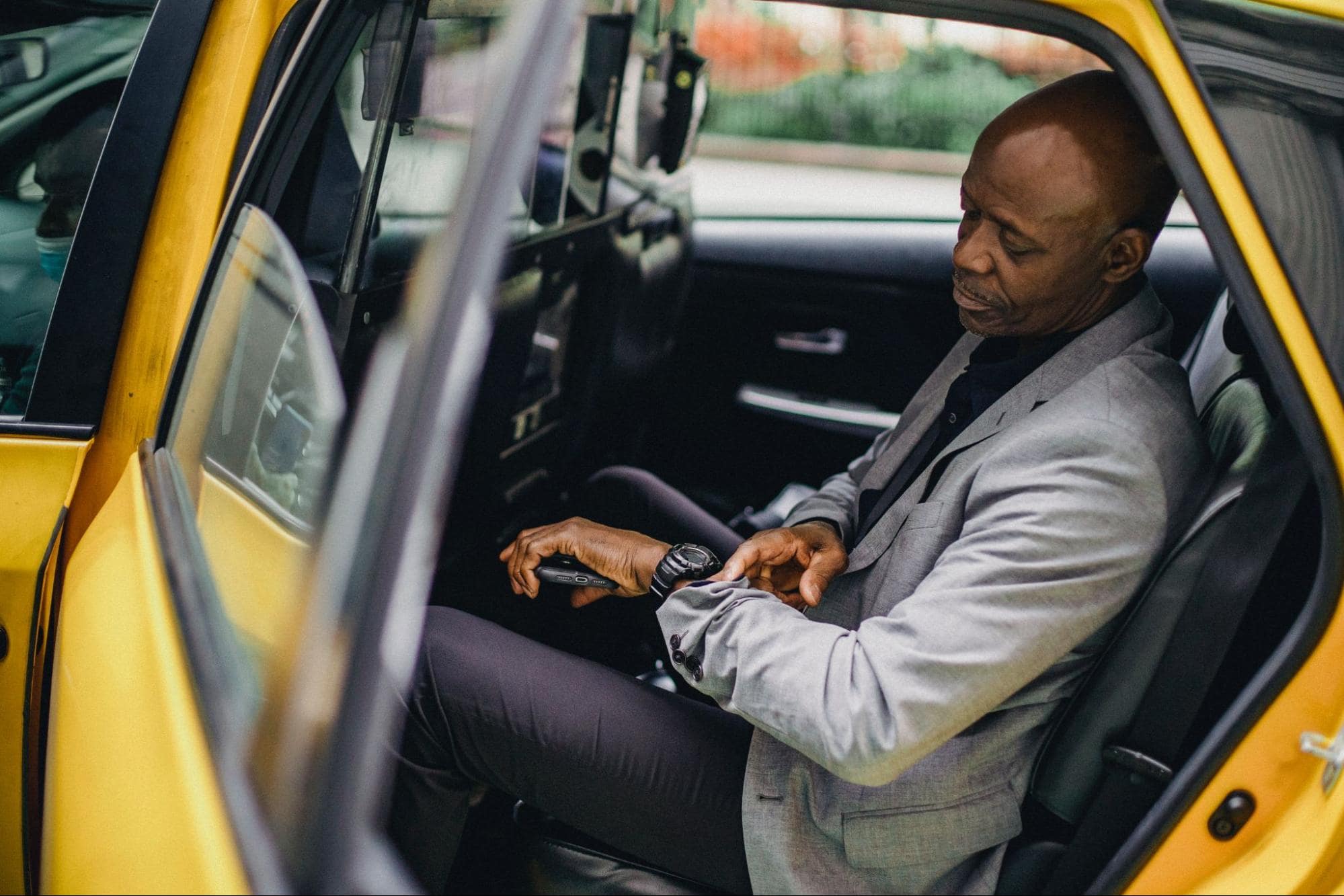 image of person looking at their watch while exiting taxi