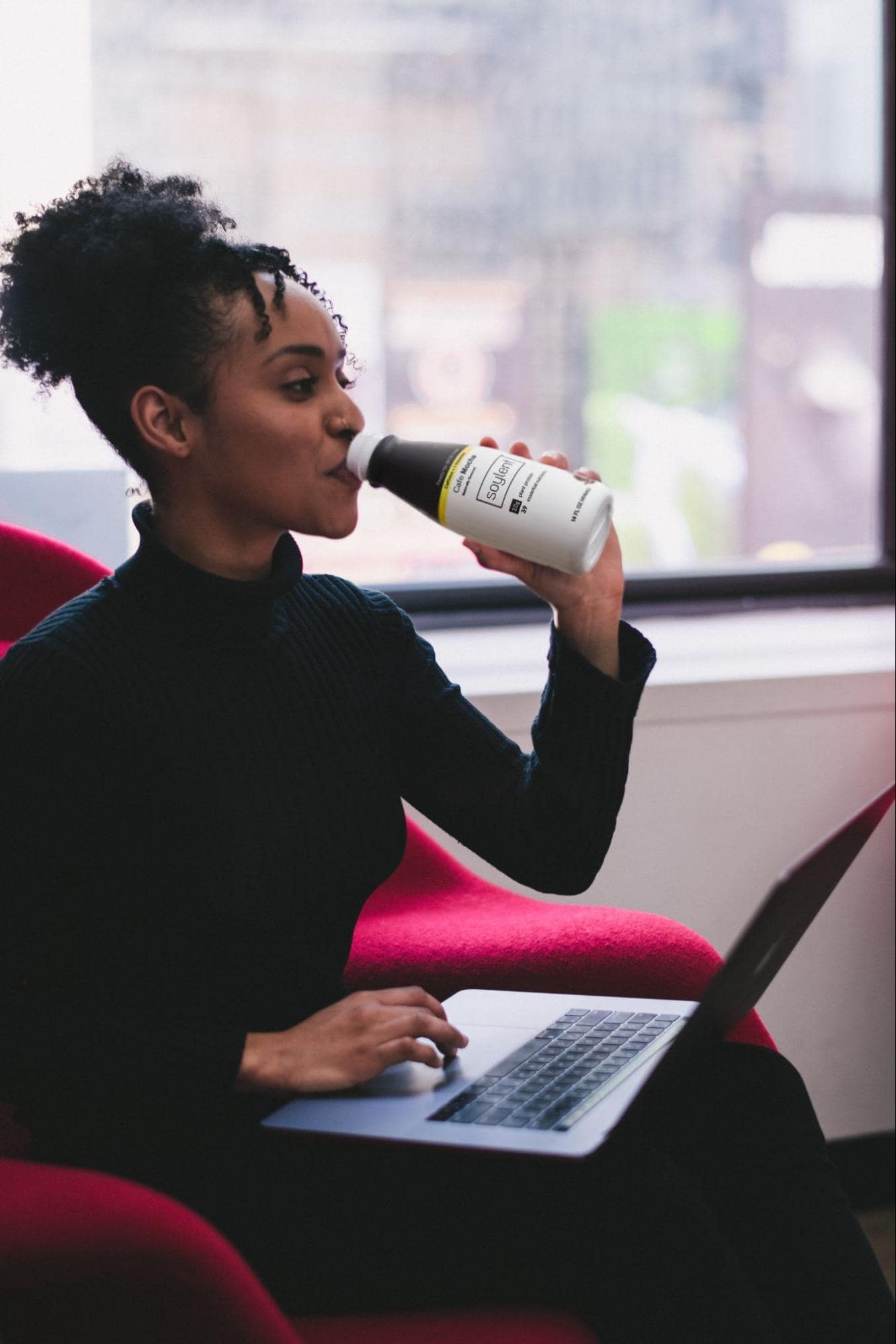 image of person drinking Soylent while working on laptop