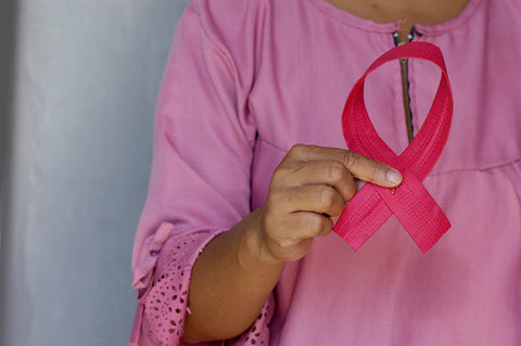 Woman holding pink ribbon in honor of breast cancer awareness