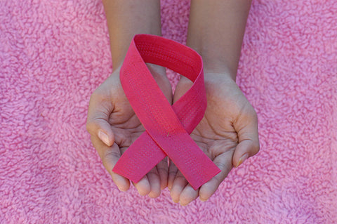Woman's hands holding a pink ribbon in honor of breast cancer awareness
