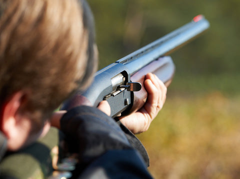 Dove hunter aiming shotgun with shell carrier