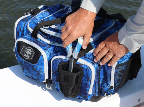 Fisherman storing fishing pliers in Calcutta Outdoors tackle bag