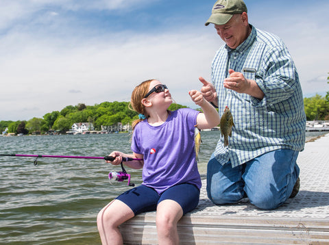 Girl catching fish with father using a spinning rod and reel combo