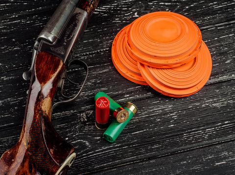 Side-by-side shotgun, shotshells and orange clay birds