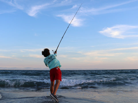 Fisherman in Calcutta shirt casting surf fishing rod