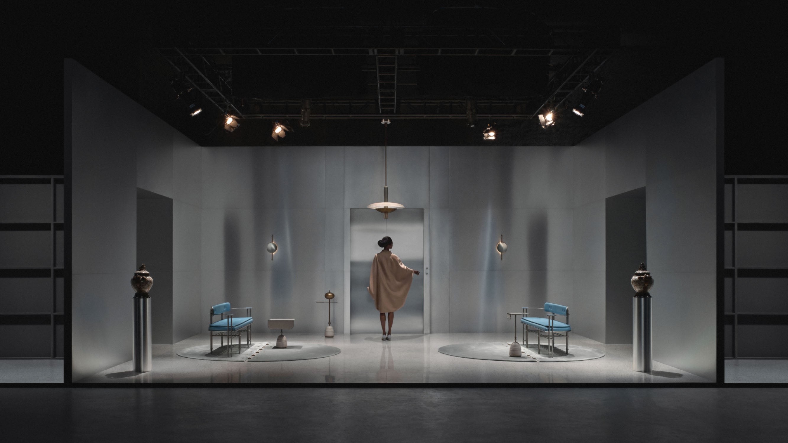 A woman walks through a room that is decorated with EPISODE settees, wall sconces and tables. 