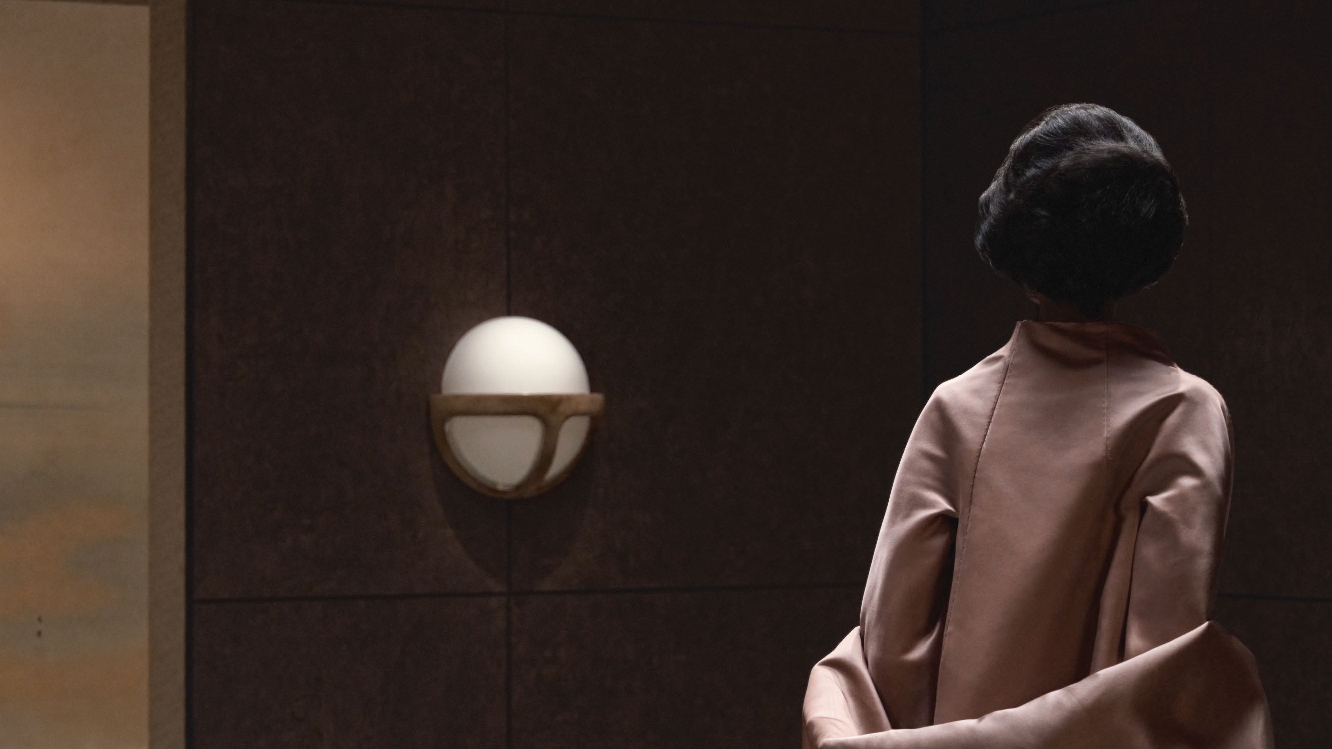 A woman walks past a REPRISE wall sconce.