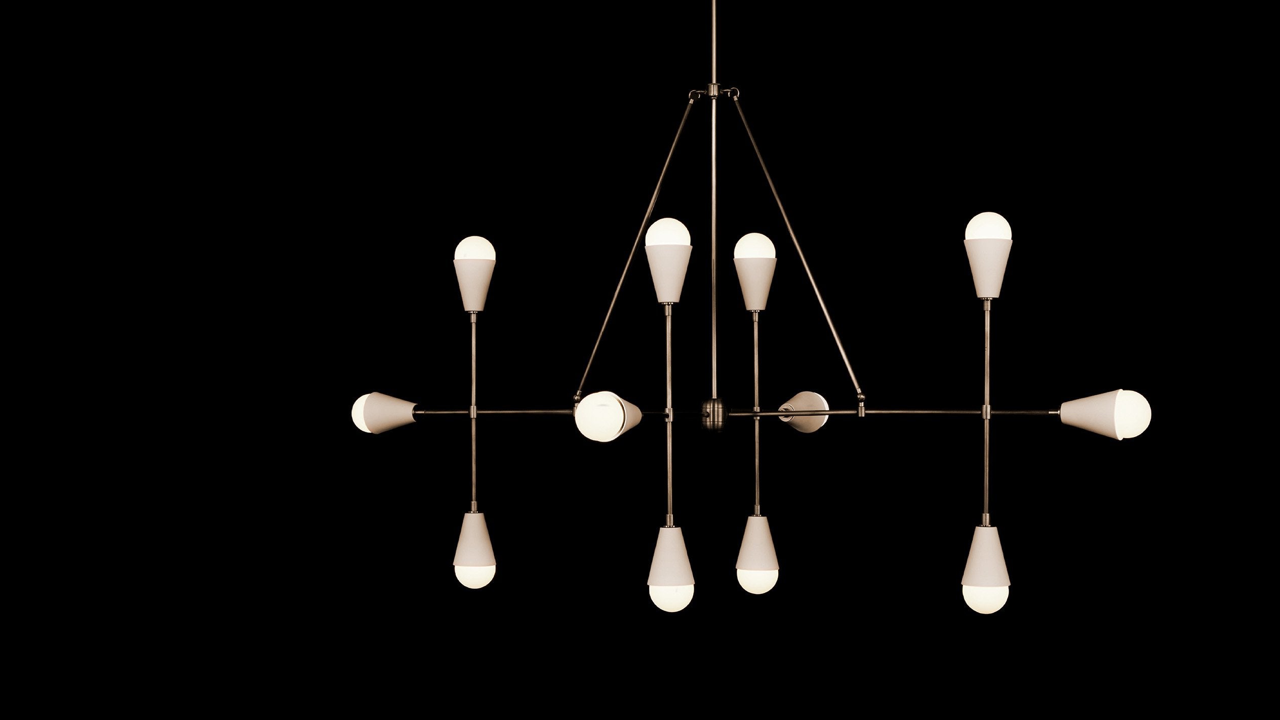 TRIAD : 12 LINEAR ceiling pendant in Aged Brass finish with Porcelain, hanging against a black background. 