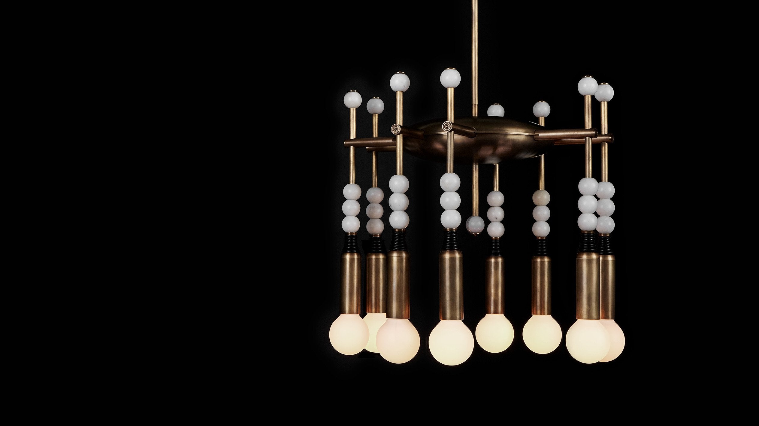 TALISMAN : 8 chandelier in Aged Brass and Black Leather with White Jade stone, against a black background. 