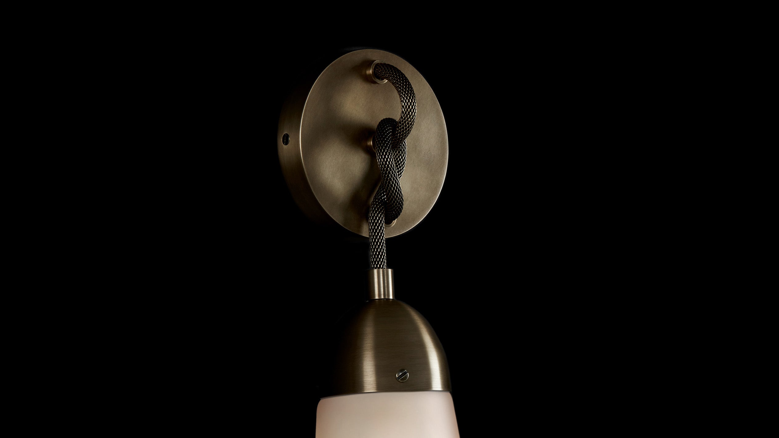Close up of a LARIAT wall sconce showing details of the Aged Brass finish.