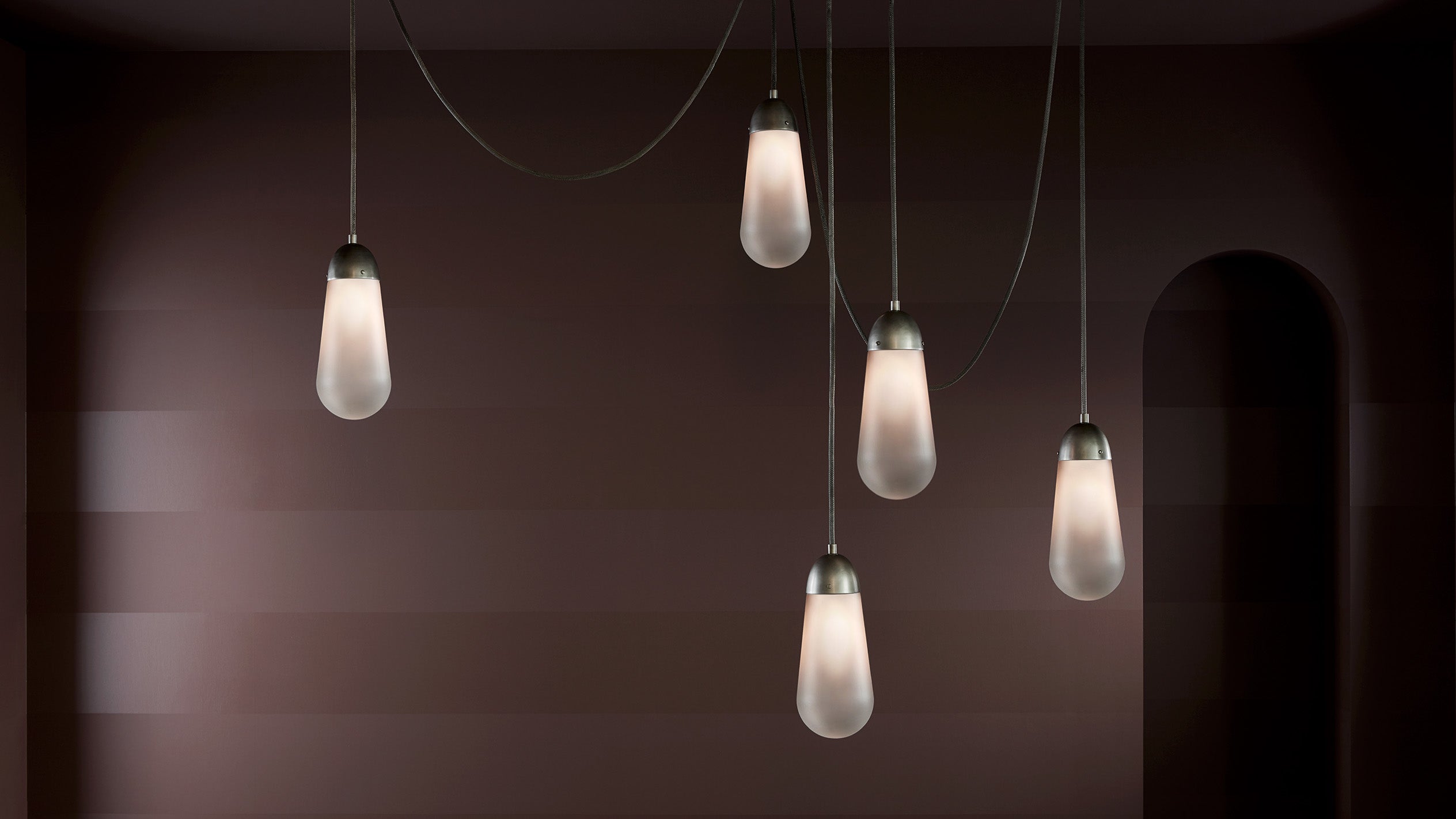 A LARIAT installation, comprised of five ceiling pendants in varying heights, in Tarnished Silver finish. 