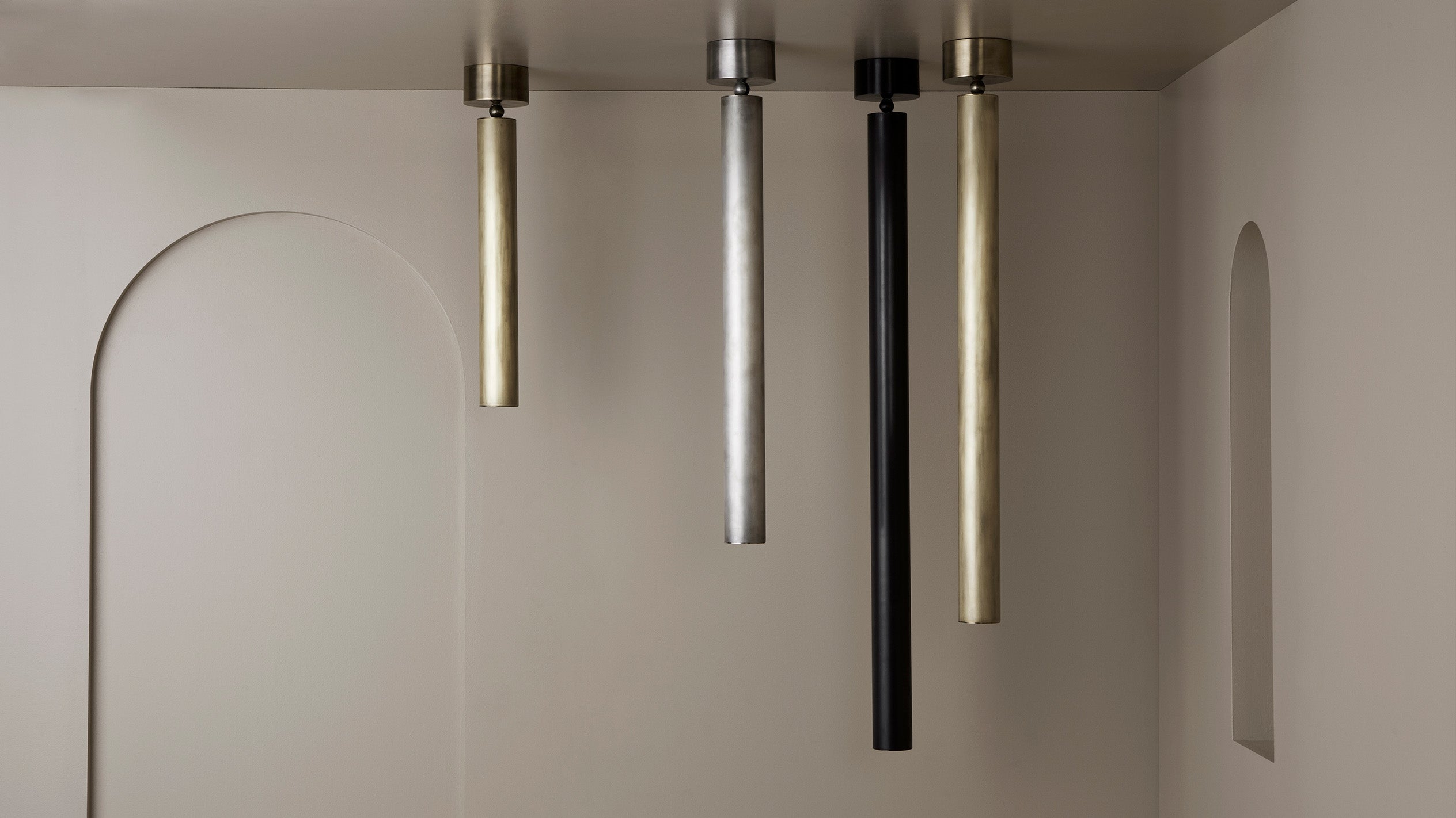 A group of four CYLINDER ceiling pendants in varying heights and metal finishes. 
