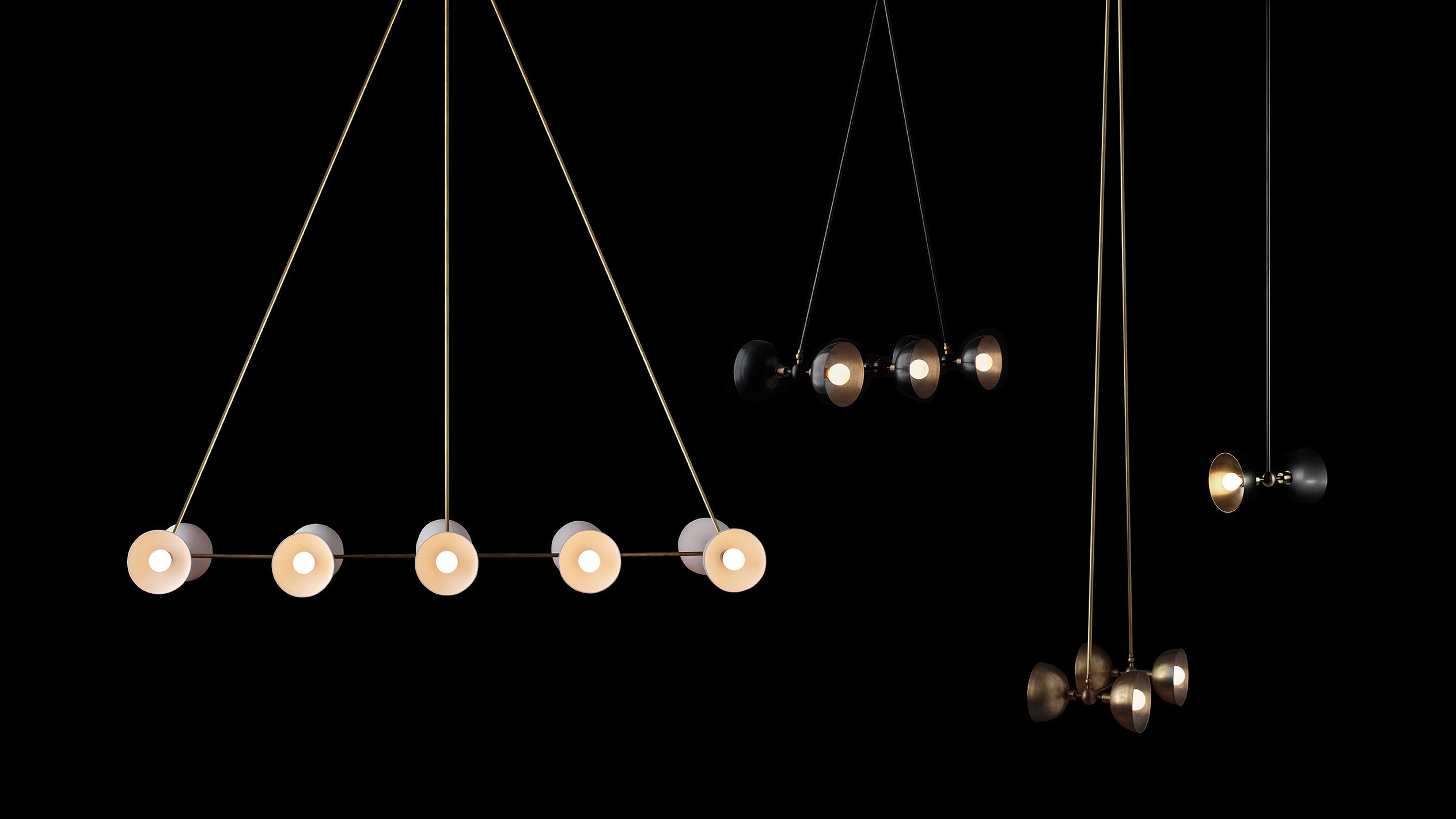 Four TRAPEZE ceiling pendants in an assortment of sizes, metal finished and materials hanging against a black background. 